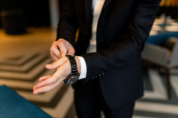 Fototapeta premium A man fastens a watch with a metal bracelet on his wrist.