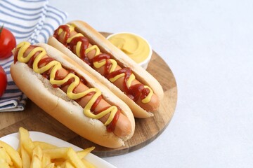 Tasty hot dogs served on light table, closeup. Space for text