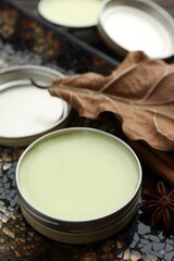 Natural solid perfume in container, spices and dry leaf on surface, closeup
