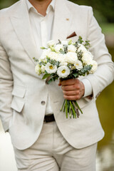 he groom holds a bouquet of white eustoma