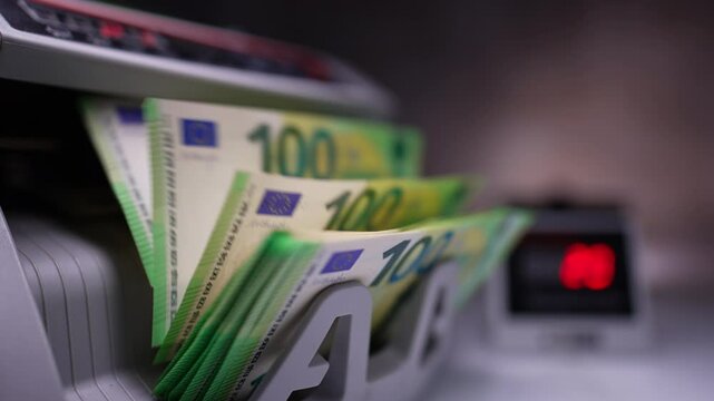 New green hundred euro banknotes being counted in cash machine. Money counting machine with bills. Close up. Blurred backdrop.