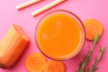 Fresh carrot smoothie in glass, rosemary and cut vegetable on pink background, flat lay