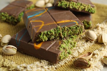 Pieces of Dubai chocolate bar with pistachios and knafeh on table, closeup
