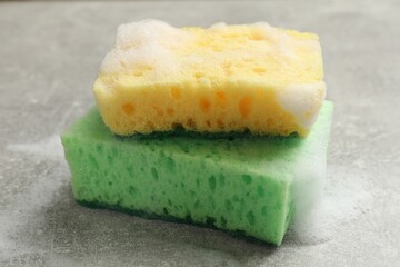 Sponges and foam on light grey table, closeup