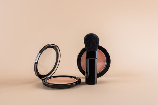 Open compact powder and brush set on a beige background