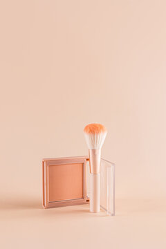 Compact face powder with brush on soft beige background