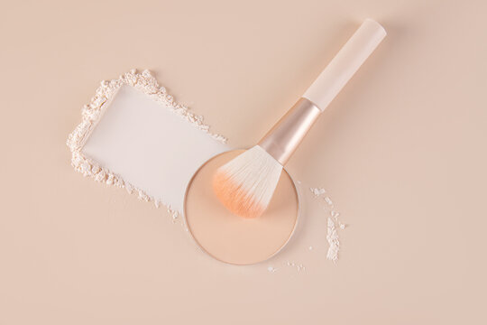 Top view of compact and loose powder with makeup brush