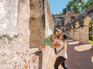 Mother plays with her daughter. Her daughter confidently throws herself into her arms and she welcomes her with joy.
