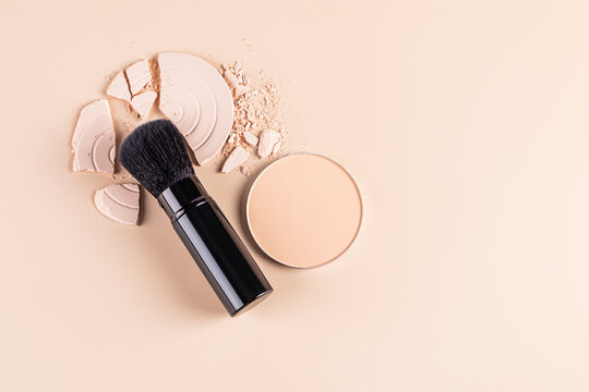 Top view of various types of face powder and a makeup brush