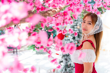 Fototapeta premium A woman celebrates Christmas,standing by the tree,lost in thought,holding a warm drink,soft lights twinkling,wrapped in festive spirit,embraced by the holiday magic