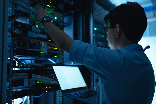 Computer engineer is setting up network in server room,Systems Maintenance Technician,Male engineer working in server room at modern data center