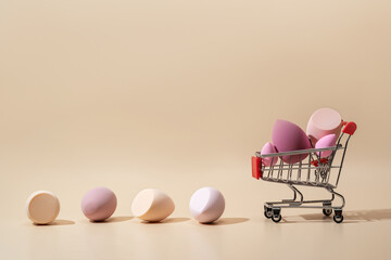 Cosmetic sponges in shopping cart against neutral background