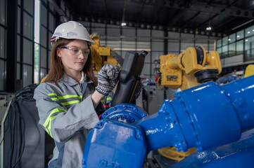 Engineer standing by robotic arm and operating machine in industry factory, technician worker check for repair maintenance electronic operation