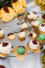 holiday treat. On the top level of the glass stand there are pieces of pineapple, decorated with bunches of red currants