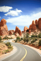 Scenic desert road through red rock formations under blue sky