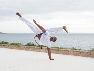 Skilled brazilian male practitioner in action demonstrating traditional capoeira by the seaside