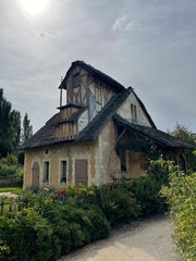 The Queen's Hamlet at the Trianon in Versailles, featuring charming rustic cottages, lush greenery, and a tranquil lake, embodying pastoral elegance and historic charm