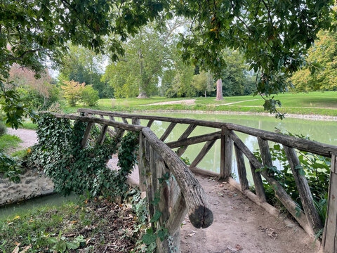 The Queen's Hamlet at the Trianon in Versailles, featuring charming rustic cottages, lush greenery, and a tranquil lake, embodying pastoral elegance and historic charm