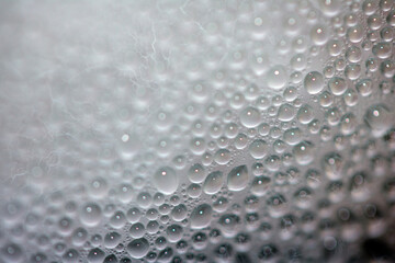 Close Up of Condensation Floating Liquid Water Bubbles and Drips on Glass from Rain