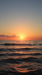 Glowing sunset reflecting off calm ocean waves, orange sky, golden hour, calm