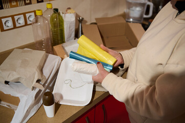 Person Sorting Recycling Materials in a Home Kitchen Environment