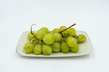 Fresh green grapes on white plate, showcasing their vibrant color and juicy texture