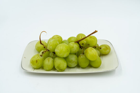 Fresh green grapes on white plate, showcasing their vibrant color and juicy texture