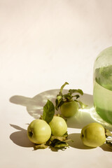 green apples with leaves on a light background.