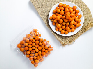 Spicy pilus with clear pouch packaging served on a white plate on burlap cloth, isolated on a white background. Perfect for snacks