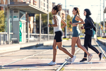 A group of three sportswomen running together through the city