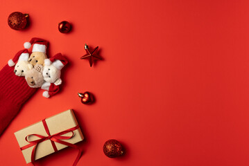 Christmas red background with bears peek out from mitten, gift box and trinkets around. Flat lay, top view. Copy space