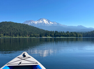 Lake Siskiyou with forested shores and snow capped Mount Shasta as seen from an inflatable kayak
