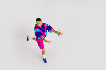 Fototapeta premium Energetic young man in retro sportswear performing a dynamic exercise on a white background