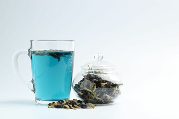 Fresh butterfly pea flower tea and dry petals on white table, closeup