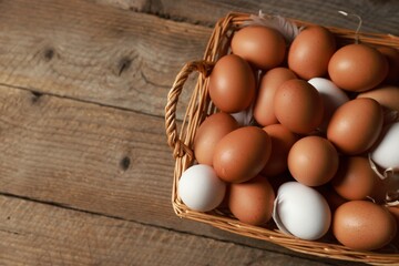 Many raw eggs in basket on wooden table, above view. Space for text