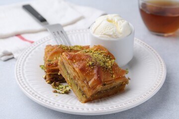 Delicious baklava with crushed nuts and ice cream on grey table, closeup