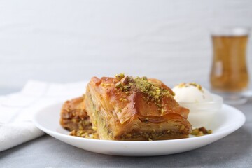 Tasty baklava with chopped nuts and scoop of ice cream on grey table, closeup