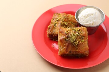 Tasty baklava with chopped nuts and scoop of ice cream on beige table, closeup. Space for text
