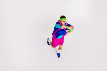 Dynamic young man in retro activewear performing a funny exercise on a white background showcasing a vintage sporty style