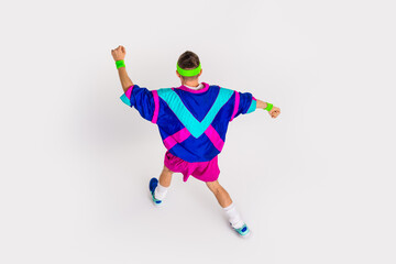 Energetic young man in retro sportswear doing dynamic exercises on white background
