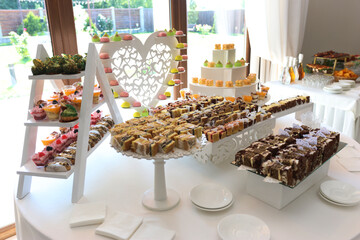 Buffet table with cakes, mousses and other sweets on wooden decor.