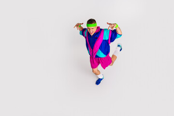 Energetic young man in vibrant retro sportswear jumps with joy and excitement, embodying athletic enthusiasm