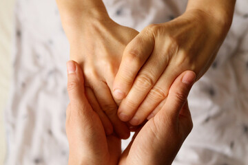 Two hands gently hold each other, conveying tenderness and warmth in a moment of connection. The soft background suggests a calm atmosphere, enhancing the intimate exchange