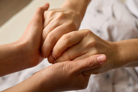 Two hands intertwine in a gesture of solidarity, symbolizing support and care. The setting conveys a sense of intimacy and reassurance between individuals
