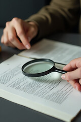 Someone is searching for a specific answer by examining some written text using a magnifying glass on their desk._00003_