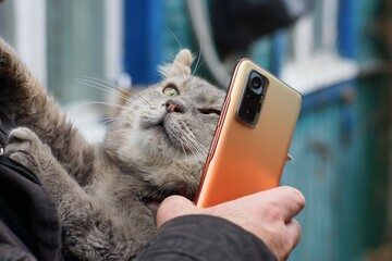 one orange with glass camera modern new mobile phone in hand of man in black jacket near ear of...