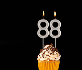 Birthday cupcake on black background - Number 88 shaped candles.