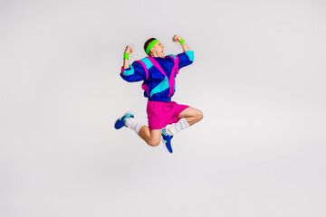 Fototapeta premium Energetic young man jumping in colorful retro sportswear on a white background