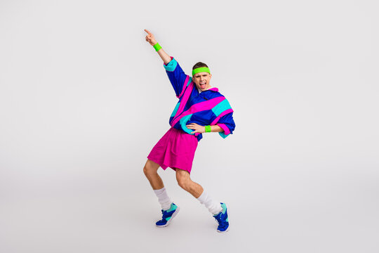 Energetic young man in retro sportswear striking a funky pose against a white background