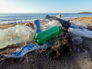 Spilled garbage on the beach of the big city. Empty used dirty plastic bottles. Dirty sea sandy shore the Mediterranean Sea. Environmental pollution. Ecological problem. Moving waves in the background